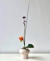 witte vaas met een eenvoudige ikebana compositie